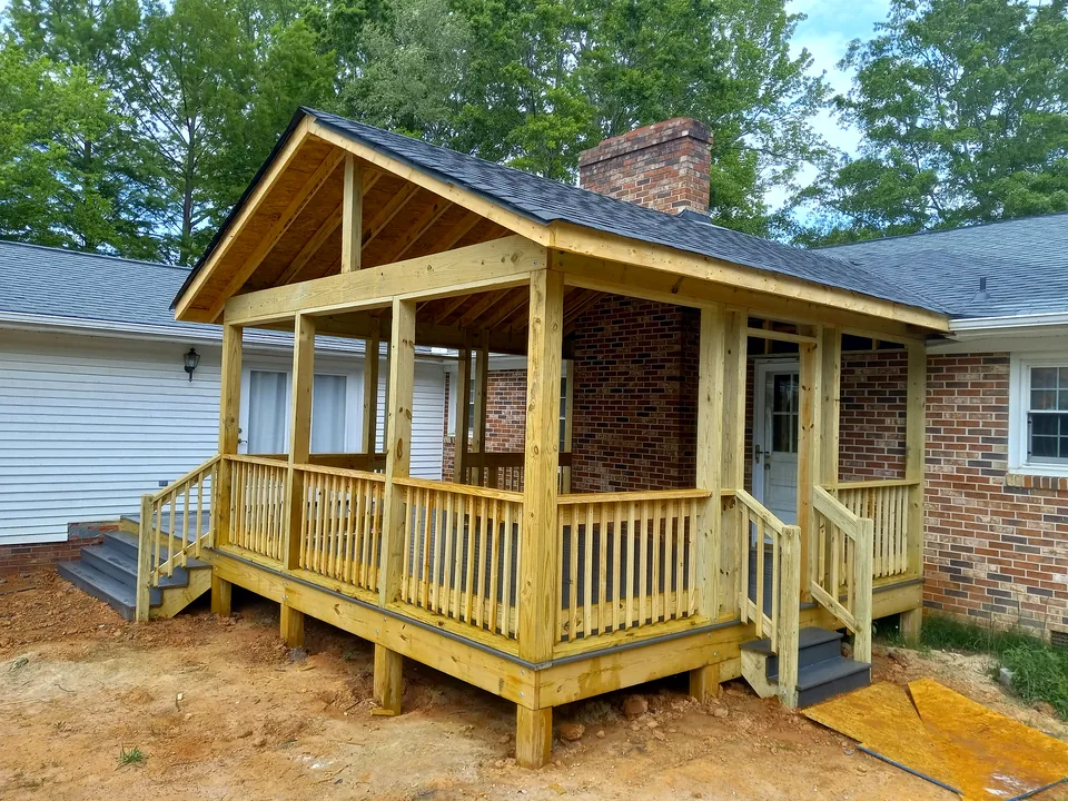 Covered wood porch with railings and exposed roof framing