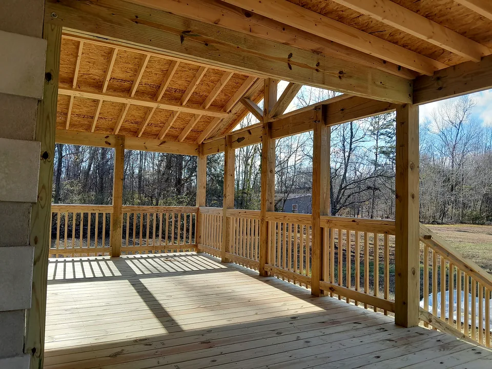 Wood porch framing and railing detail with shaded deck boards