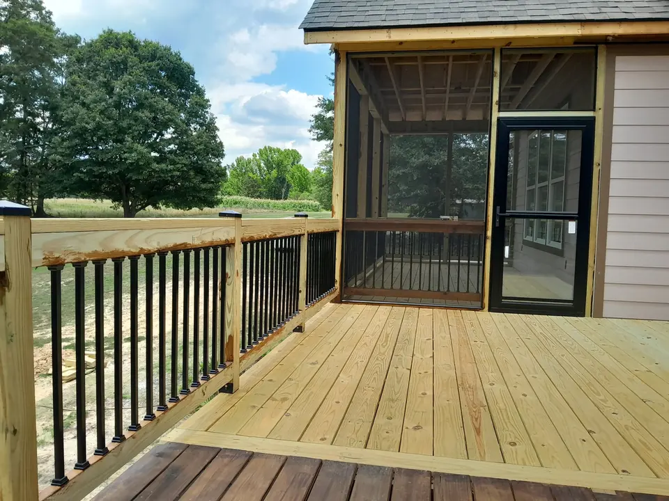 Wood deck with railing leading to a screened porch door