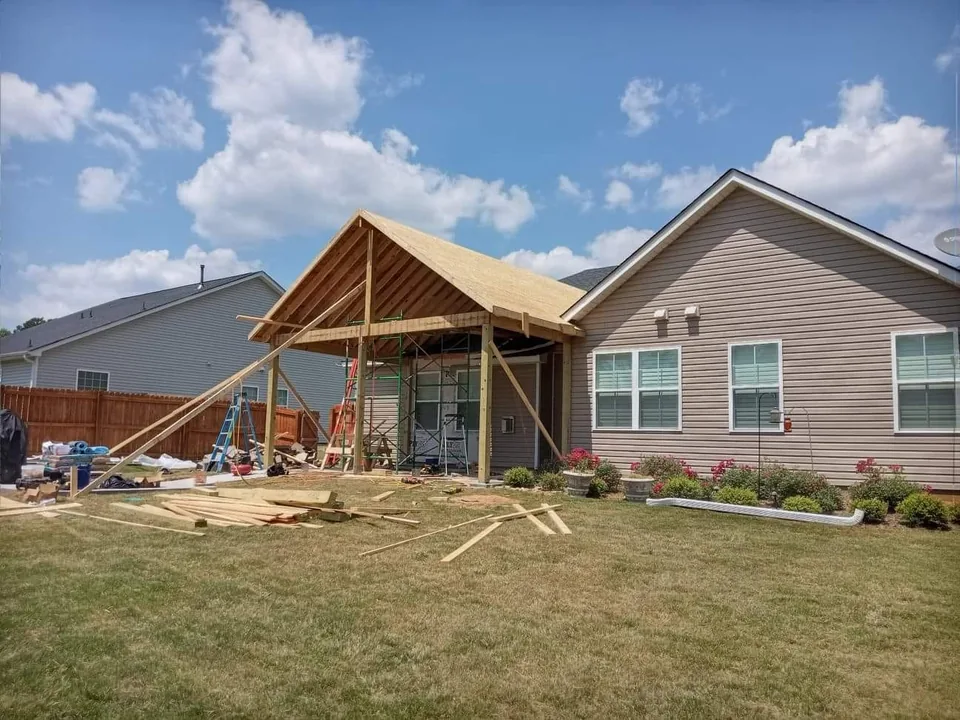 Home add-on framing tied into the back of a house with roof structure open